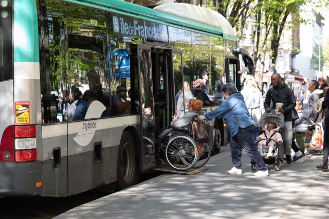 Bus avec rampe PMR pour permettre une dame à mobilité réduite de monter à l'intérieur.